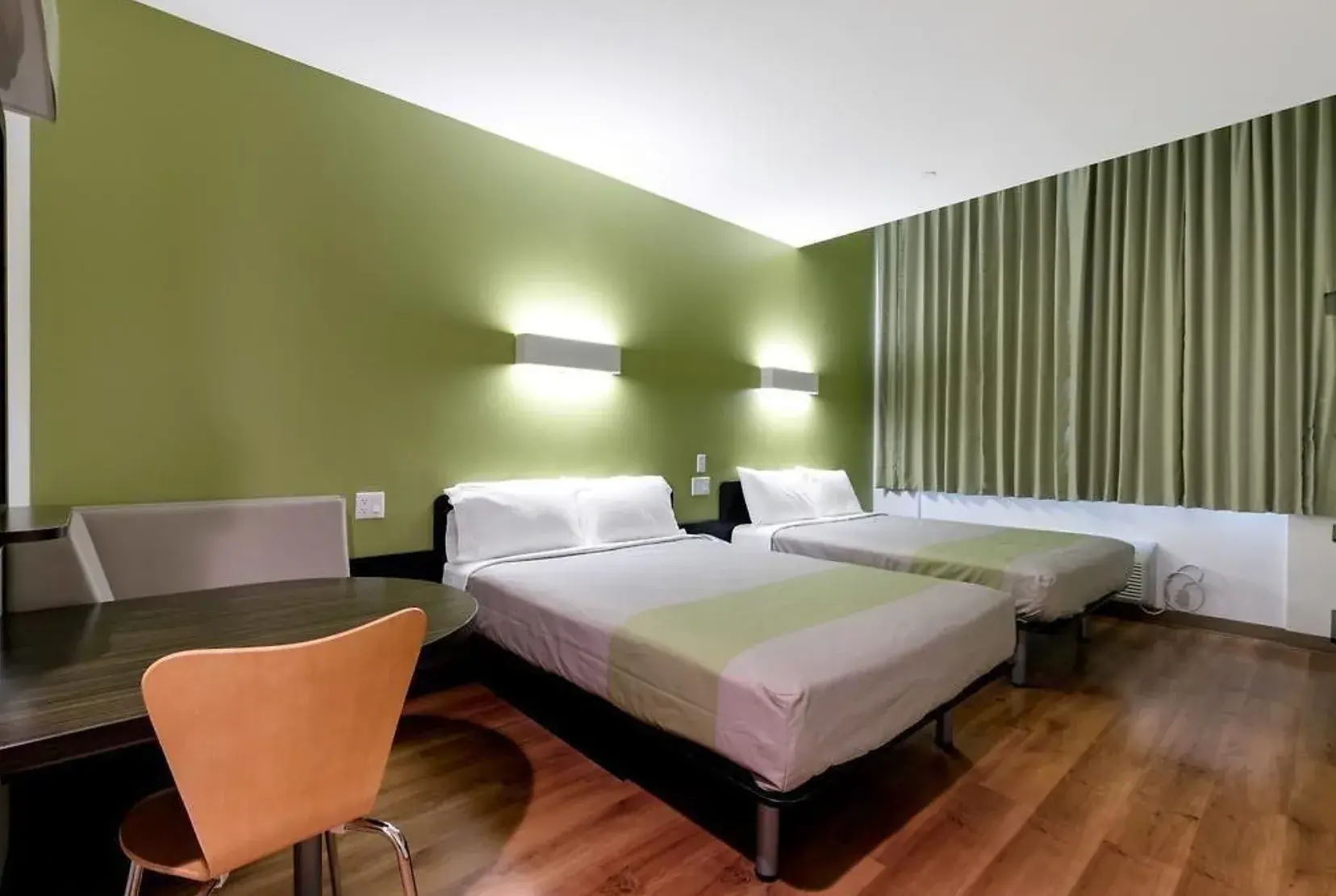 Family Room im Feather Factory mit zwei Betten, Tisch und grünen Vorhängen