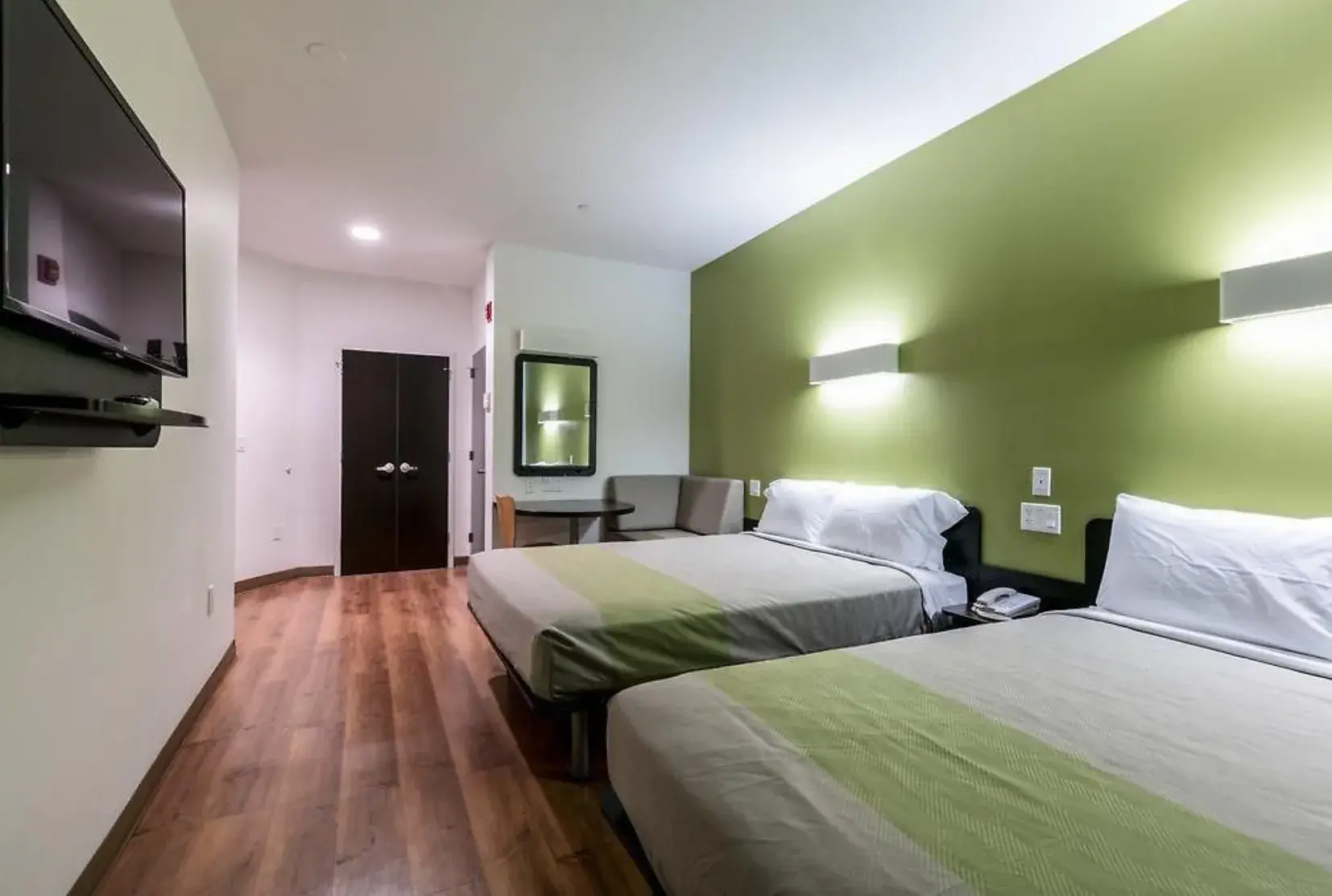 Queen Room with Two Queen Beds mit zwei Betten, grüner Wand und Sofaecke
