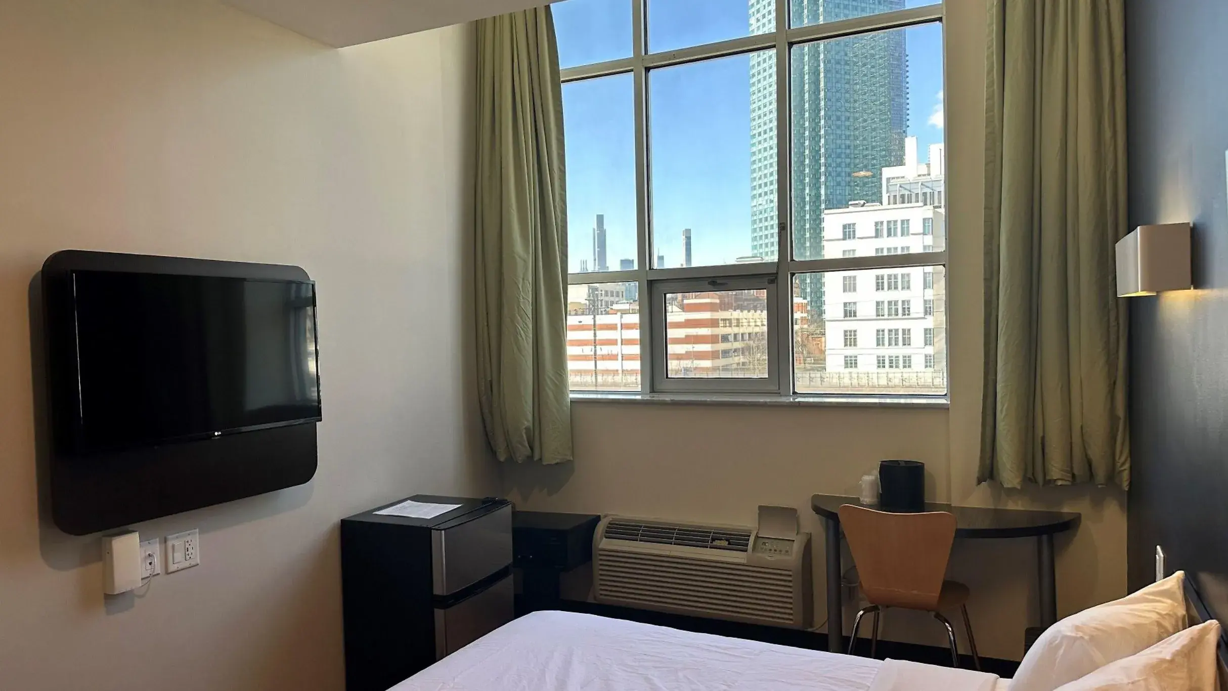 Barrierearmes Zimmer mit großem Fenster zu den Hochhäusern, Fernseher, Minikühlschrank und Schreibtisch