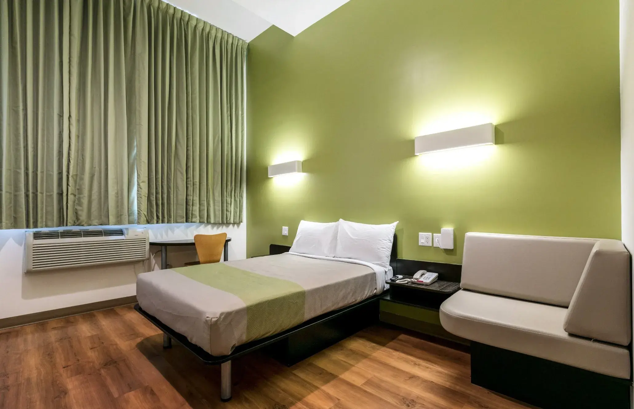 Zimmer im Feather Factory Hotel mit Doppelbett, gepolsterter Sitzbank und Schreibtisch am Fenster