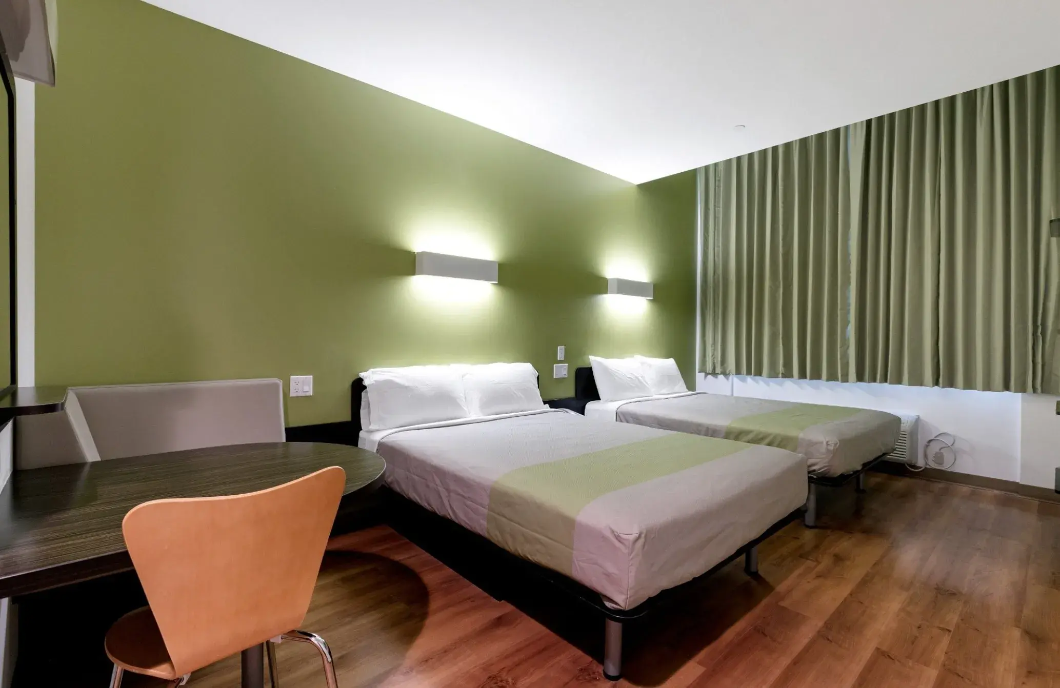 Zimmer mit zwei Doppelbetten, rundem Tisch und Stuhl
