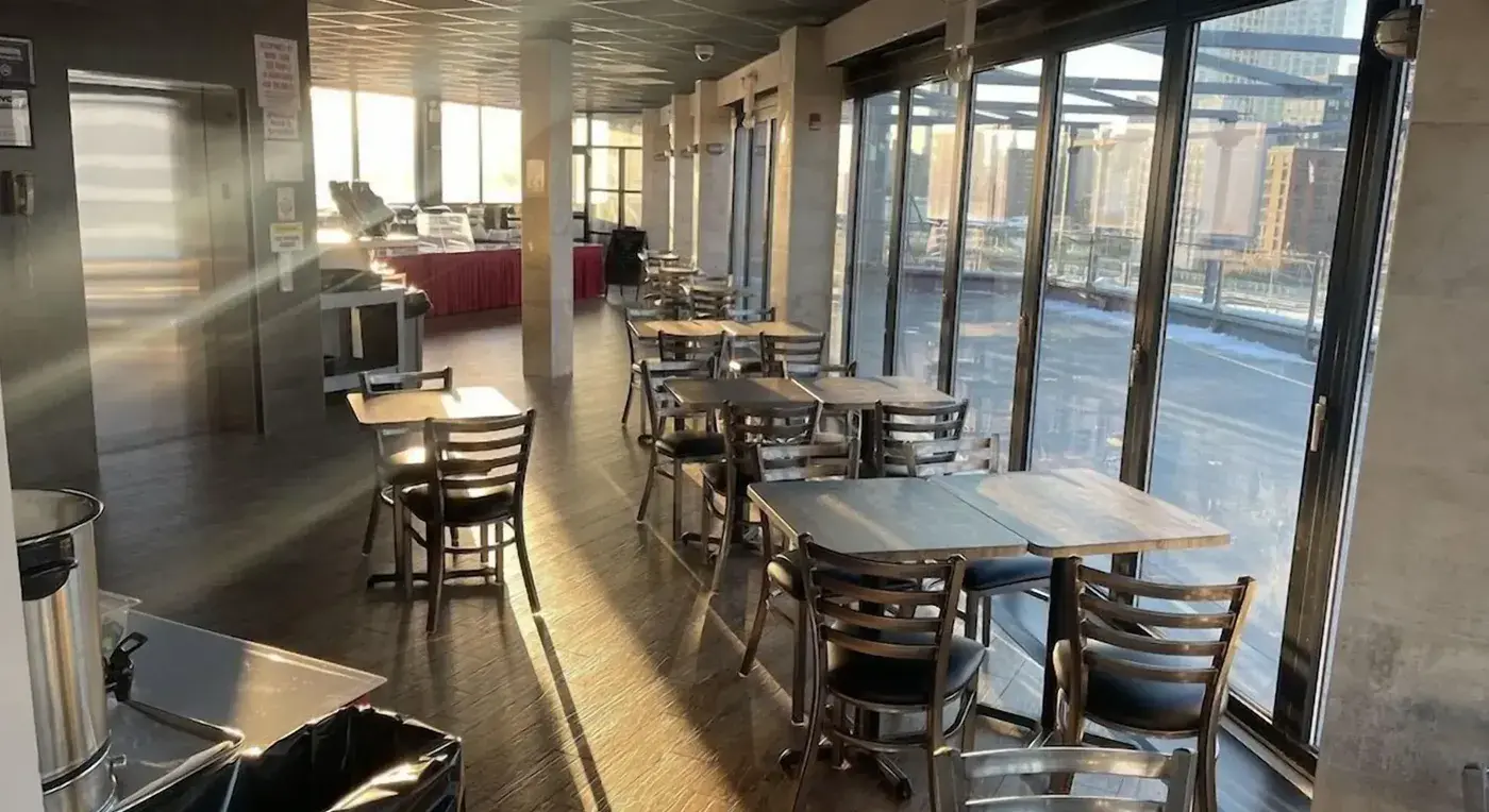 Frühstücksraum mit Fensterfront zur Terrasse und Blick auf die Gebäude der Stadt